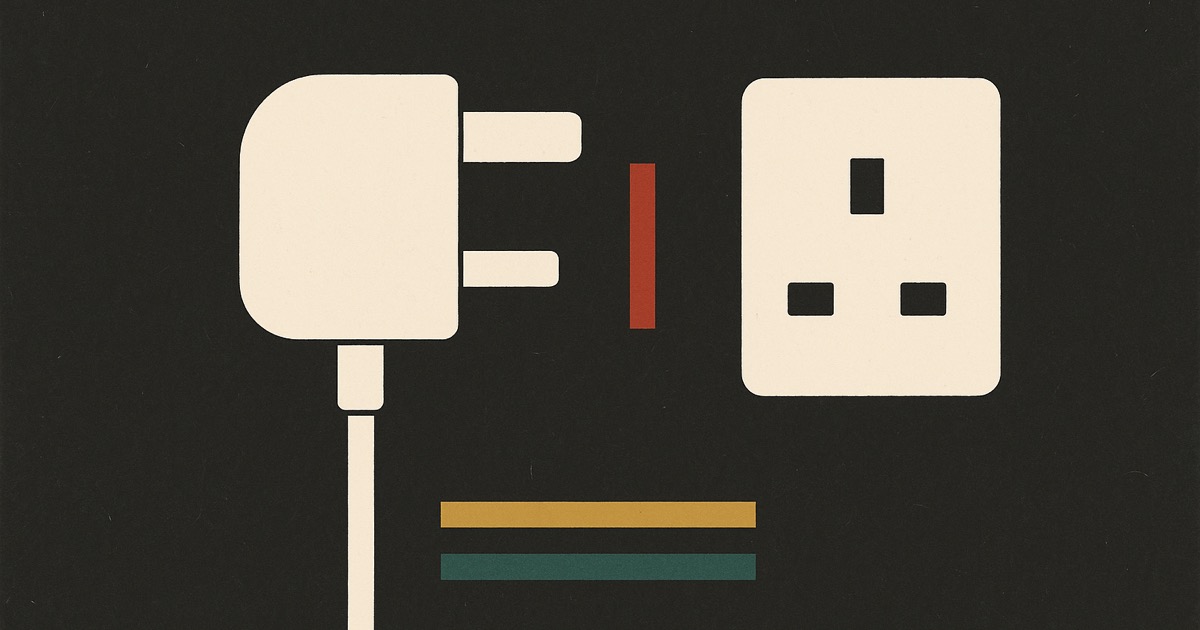 An ivory plug and socket facing each other with a red bar standing in the gap, on charcoal