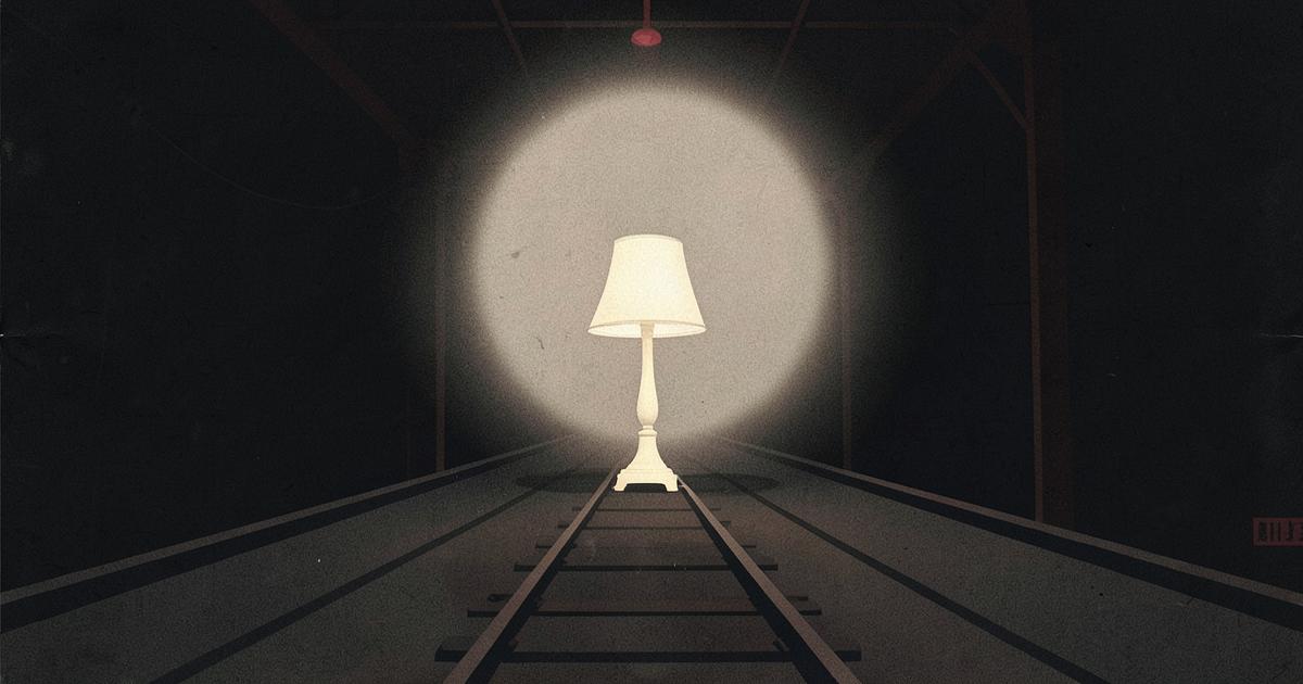 A single lamp lighting a set of rails running into a dark warehouse, in ivory on charcoal